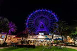 An image of a corporate event at ICON Park with a tent and furniture in front of the iconic Orlando Eye ferris wheel.