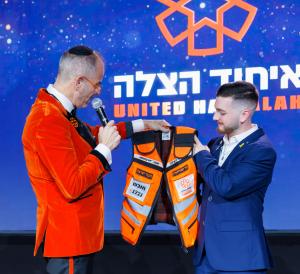 President & Founder of United Hatzalah presenting former hostage Bar Kuperstein with his new personalized medic vest