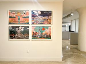 Four framed Philadelphia cityscape prints by Mega Asellia hang in a two-by-two grid on a light-colored wall in a modern office-like space with exposed ductwork.