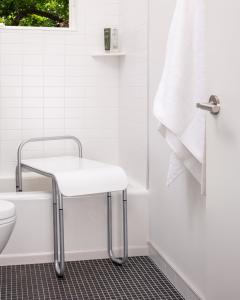 The Judith Bench helps keep caregivers and loved ones safe by providing assistance when needed. This image shows the Judith bench with a solid frost seat and adjustable chrome frame. The bench is positioned in a bathtub for bath or shower use.
