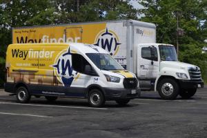 Yellow and navy Wayfinder Moving Services truck on Buffalo city street with modern buildings in background