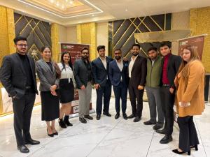 Mr. Sidharth Dhingra and Mega Realty Max team seated around a table in a formal meeting with clients, discussing property opportunities in an upscale conference room with gold-accented interiors.