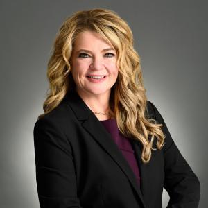 Professionally posed photo of Steph Gallo looking at the camera with her hand on her hip