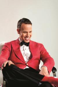 Designer Miles Redd seated wearing formal red jacket.