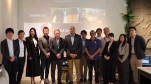 A diverse group of clinical researchers and team from Robotimize Group posing in front of a digital presentation screen during the INSIGHT Symposium in Singapore.