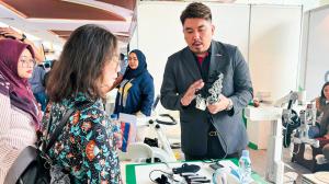 Even Koh explaining the mechanics of a robotic neurorehabilitation glove to clinical professionals at a healthcare technology exhibition.