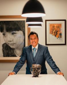 Johnessco Rodriguez, Fair Director of ARQA ART FAIR, pictured with artworks from his personal collection, including an object from the pre-Columbian city of Teotihuacan, Mexico, and contemporary framed artworks.