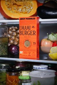 A lone Umami Burger perches patiently on the edge of a fridge shelf.