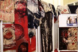 Hanging textile artworks by Sonali Dharmawardena created in collaboration with Caterina Roppo, featuring abstract red, black, and natural dye patterns, displayed as part of the EU–Sri Lanka Craft Matchmaking Programme.