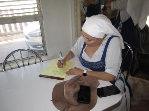 Sister Esme sitting at the kitchen table making a list on a note pad