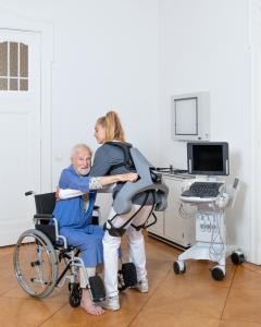 Nurse wearing an Exia exoskeleton helping a patient out of a wheelchair