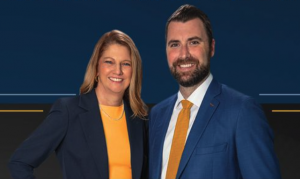 Image of two attorneys. On the left is Female attorney Bonnie Rickert. She has blonde hair and wears a blue jacket with yellow blouse. Attorney Alex Hilliard is on the right. He is a caucasian man with dark brown hair and beard. He wears a dark suit, whit