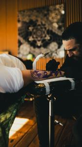 A photo of tattoo artist Dillon Forte at work tattooing a client