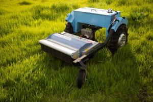 A small blue two-wheel electric tractor is in a field, paused between tasks.