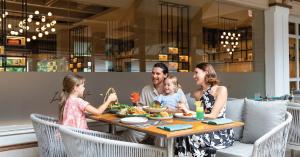A family seated at an elegant dining table with various dishes and drinks at Courtyard by Marriott Phuket, Patong Beach Resort.