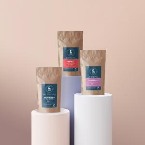 Three bags of &BACK COFFEE displayed on pedestals, featuring Signature Medium Roast, Impact Dark Roast, and Inspiresso Espresso blends.