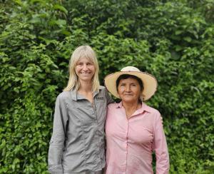 Roxanne Joyal of &BACK COFFEE standing beside Nancy, a woman coffee farmer in Ecuador, outdoors in a green landscape.