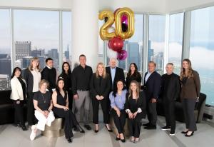 Suite Home Team Celebrating 20-Year Anniversary, Group Photo with Skyline Views of Chicago.