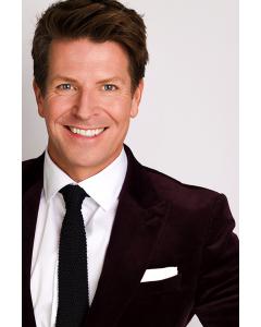 Wellness expert Gordon Fraser smiles broadly at the camera wearing formal, black tie clothing.