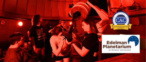 Participants engage with a telescope in a dimly lit observatory, promoting hands-on astronomy experiences at the Edelman Planetarium.