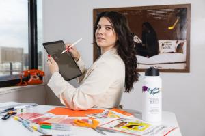 A Creative Repute employee reviews color palettes and sketches on a tablet at a workspace, illustrating early brand planning and creative preparation for businesses anticipating increased visibility during global events.