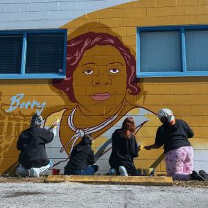 Four girls working on filling in the outlines of the mural