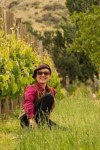 a smiling woman sitting in a vineyard