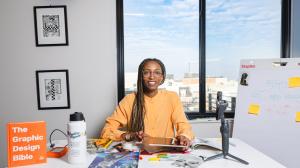 Creative Repute Founder and CEO, Nile Livingston - a professional working at a desk with a tablet and planning materials in a bright studio workspace.