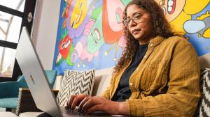 A professional at Creative Repute working on a laptop in a creative office environment with colorful artwork in the background.