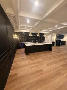 completed residential basement featuring custom cabinetry, a large island, coffered ceilings and recessed lighting