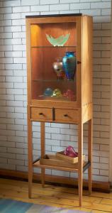 Standing tall on graceful legs, this meticulously constructed lighted cabinet is crafted in solid Pennsylvania cherry with dark wenge accents.