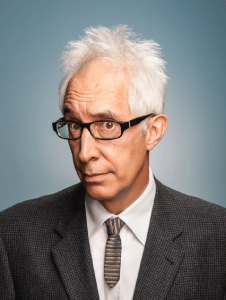 A more somewhat serious headshot of Post with glasses and hair on end