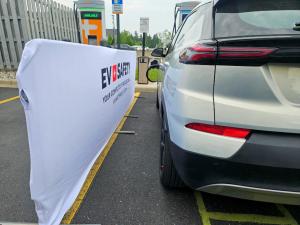 An electric car at a charger with a FireGuard Fire Resistant Parking Barrier to its left.