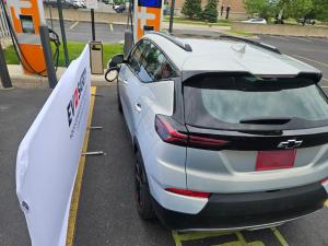 Raised view of an electric car at a charger with a FireGuard Fire Resistant Parking Barrier to its left.