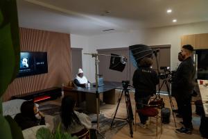 Production crew with cameras and lighting equipment filming in Beige AI studio