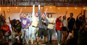 Students on stage with raised hands during an evening program at Mt. Gilead Bible Camp and Conference Center in Sebastopol, California.