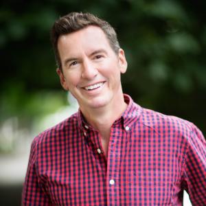 Headshot of Jon Leslie, Director of Consulting at ProInfoNet, smiling and wearing a red checkered button-down shirt outdoors.