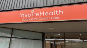 A grey building has an orange sign with two lines of text. The top line says InspireHealth, the second says Supportive Cancer Care.