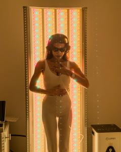 Guest uses the Lumati Recharge Portal at Spa Alila, standing in front of a multi-wavelength red light therapy panel while wearing protective goggles and headphones