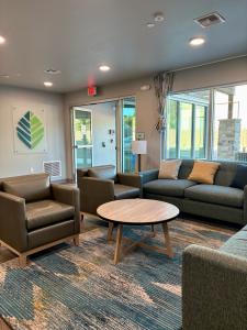 Lobby interior of the newly constructed WoodSpring Suites Santee – San Diego Northeast, with contemporary seating, a round coffee table, and large windows providing natural light.