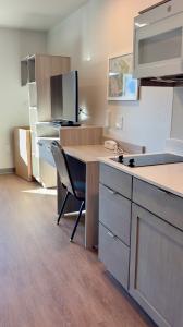 Interior of a guest suite at WoodSpring Suites Santee – San Diego Northeast showing a kitchenette with cooktop and microwave, built-in desk, television, and storage cabinetry.