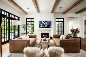  Interior view of the luxury living room at 4536 N 49th Pl, showcasing a massive brick fireplace, custom wood ceiling beams, and large windows that flood the open-concept space with natural light
