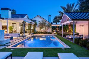 A luxury resort-style backyard in Arcadia featuring a large swimming pool, spa, and a sprawling travertine patio with a built-in barbecue and expansive covered outdoor living area