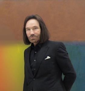 Józef Hubert Gierowski against a multicolored background. Józef Hubert Gierowski is wearing a suit.