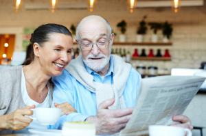 Couple drinking coffee while reading newspaper Sudoku puzzle.