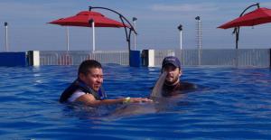 Guest and trainer swim with a bottlenose dolphin at Marineland Dolphin Adventure in St. Augustine—part of the Swim with Dolphins St Augustine programs.