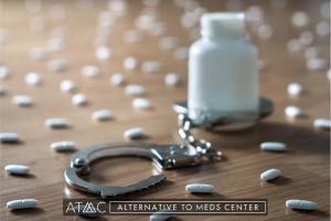 Handcuffs and scattered prescription pills on a table representing the concept of medication dependence and the impact of long-term drug use.