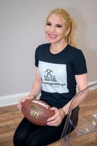 Natanya Wachtel kneeling and holding an American football, wearing a #Game Mindset T-shirt.