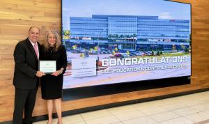 Illinois State Representative and Rosemont Mayor Bradley A. Stephens joins Lisé Puckorius, CAE, CEO of the OLC, at the Rosemont Village Hall next to a large monitor showing the OLC building.