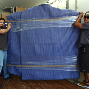 All Cal Moving Systems team smiling and holding a delivered package, demonstrating professional and dependable moving services in Visalia, California